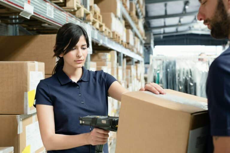 Warehouse workers using barcode scanner on box in distribution warehouse